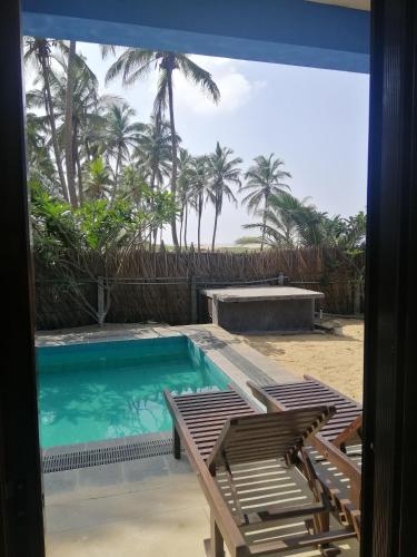 a pool with two chairs and a table and palm trees at Nayan's Paradise in Kottanitivu
