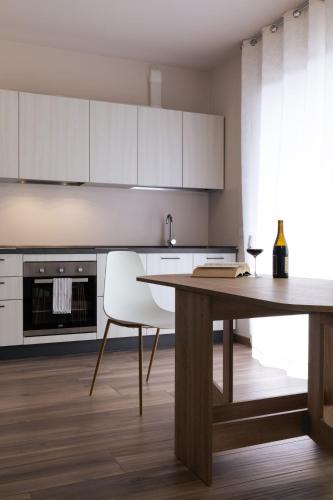 a kitchen with a wooden table and white cabinets at Appartamenti Del Borgo in Borgosesia