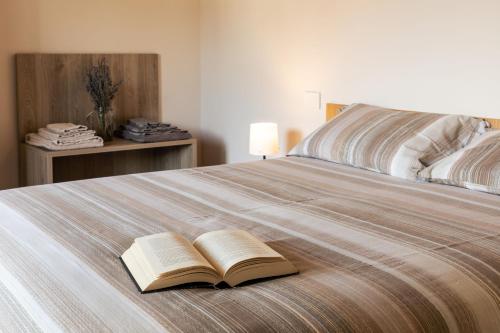 an open book laying on top of a bed at Appartamenti Del Borgo in Borgosesia