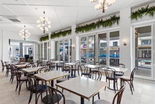 a restaurant with tables and chairs and windows at Ramada by Wyndham, Hamilton City Center in Hamilton