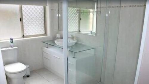 a white bathroom with a shower and a toilet at Norfolk Grove Apartment - Hosted by Burleigh Letting in Gold Coast