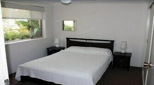 a bedroom with a white bed and a window at Norfolk Grove Apartment - Hosted by Burleigh Letting in Gold Coast