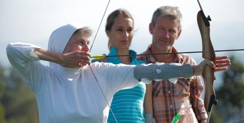 two men and a woman holding a bow and arrow at Curhaus Bad Kreuzen in Bad Kreuzen
