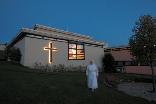 a woman standing in front of a church with a cross in the window at Curhaus Bad Kreuzen in Bad Kreuzen