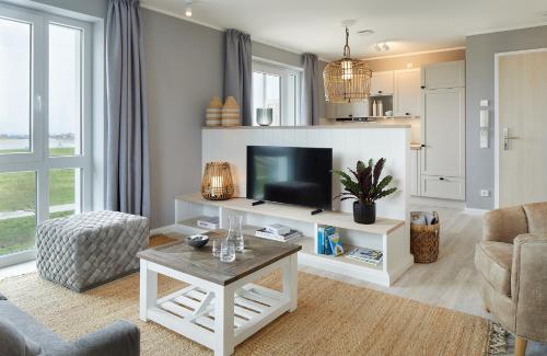 uma sala de estar com uma televisão, um sofá e uma mesa em Beach Apartments Büsum em Büsum