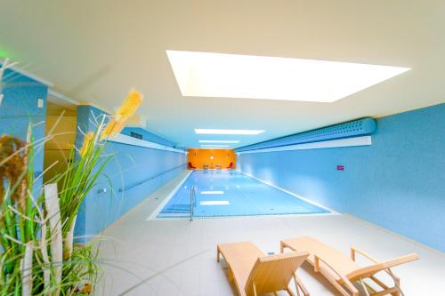a swimming pool in a building with chairs and a ceiling at Curhaus Bad Kreuzen in Bad Kreuzen