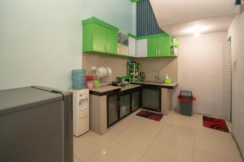 a small kitchen with green cabinets and a refrigerator at RedDoorz Syariah near Pantai Bali Abdya Blang Pidie in Blangpidie