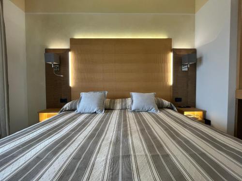 a bedroom with a large bed with two blue pillows at Hotel Mare in Lignano Sabbiadoro