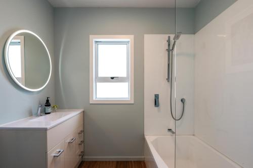a bathroom with a shower and a sink and a mirror at Oneroa Coastal Classic - Coast & Country in Oneroa