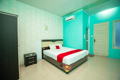 a bedroom with blue walls and a bed with a red blanket at RedDoorz Syariah near Pantai Bali Abdya Blang Pidie in Blangpidie