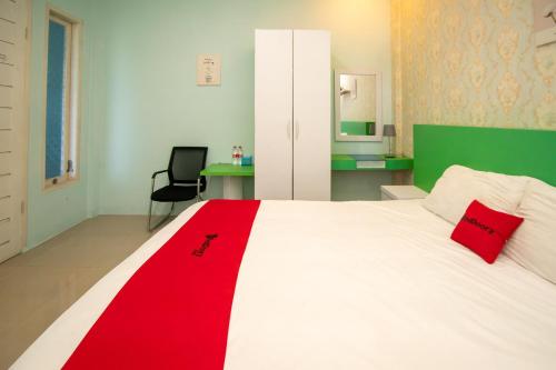 a bedroom with a white bed with a red blanket on it at RedDoorz Syariah near Pantai Bali Abdya Blang Pidie in Blangpidie