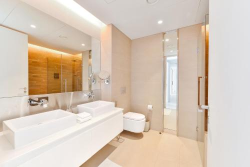 a white bathroom with a sink and a toilet at Posh 2 BR Oceanfront Apt in the Heart of Bluewaters Island in Dubai