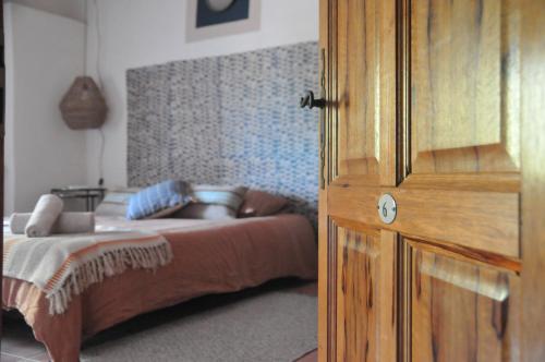 a bedroom with a bed and a wooden door at Le Mas des Perrines Maison d’Hôtes in Pernes-les-Fontaines