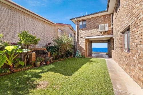 a backyard of a brick building with a grass yard at 1 15 Dalmeny Drive Kianga in Kianga