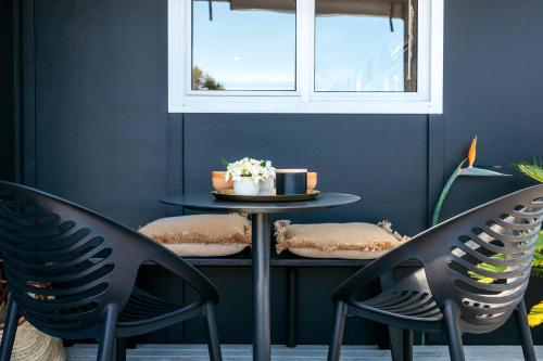 two chairs and a table in a room with a window at Oneroa Coastal Classic - Coast & Country in Oneroa