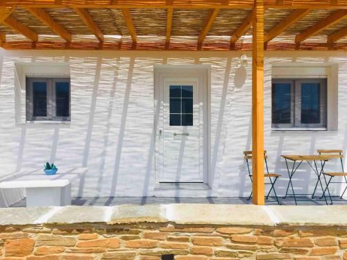a white house with a table and chairs and a wooden roof at New, Modern and Cozy apartment in Gavrio in Gavrion