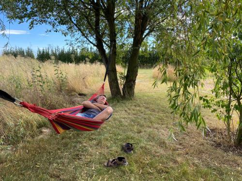 a man laying in a hammock in a field at Fewo TURMZIMMER im Rittergut Leppersdorf bei Dresden in Leppersdorf