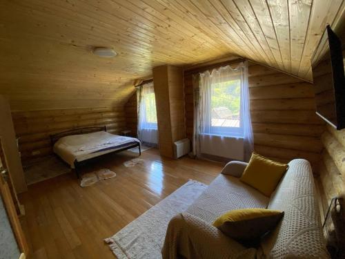 una sala de estar con sofá en una cabaña de madera en Приватна садиба GREEN HOUSE en Mizhhirʼʼya