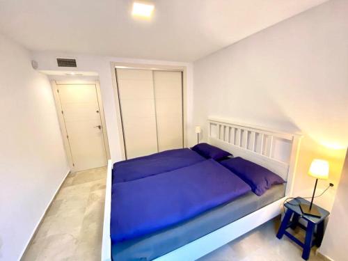 a bedroom with a blue bed in a white room at Apartment Alcaidesa in La Alcaidesa