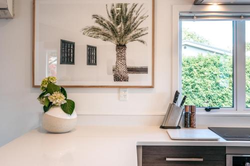 a kitchen with a palm tree picture on the wall at Oneroa Coastal Classic - Coast & Country in Oneroa