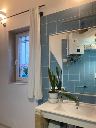 ein Bad mit einem Waschbecken, einem Spiegel und einem Fenster in der Unterkunft Casa Bandini in Galatone