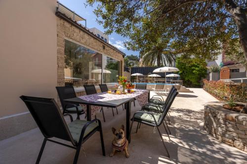 einen Tisch mit Stühlen und einen Hund auf einer Terrasse in der Unterkunft Casa Allegra in Mali Lošinj