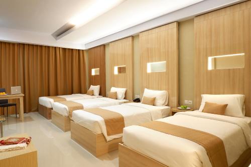 a hotel room with three beds and a desk at Sahid Azizah Syariah Hotel and Convention Kendari in Lepoleop