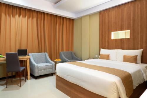 a hotel room with a bed and a desk and chair at Sahid Azizah Syariah Hotel and Convention Kendari in Lepoleop