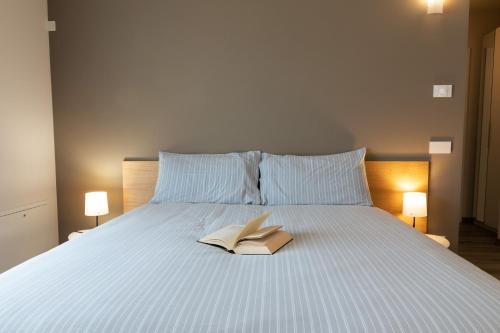 a book sitting on top of a bed with two lamps at Appartamenti Del Borgo in Borgosesia