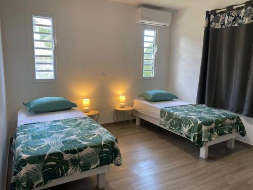 two beds in a room with two windows at Ana iti Lodge PAEA Tahiti in Paea