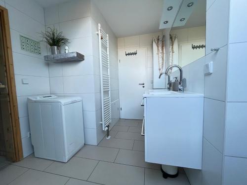 a white bathroom with a sink and a washing machine at Penthousewohnung Küstenzauber 22 in Großenbrode