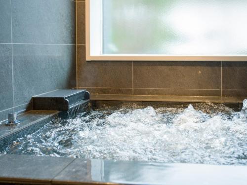 een badkamer met een bad gevuld met water bij Rakuten STAY VILLA Yatsugatake - 101 Stylish Design - in Hokuto