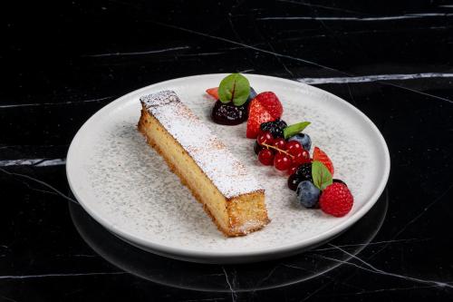 un morceau de gâteau avec des fruits sur une assiette dans l'établissement Ego SPA, à Birštonas