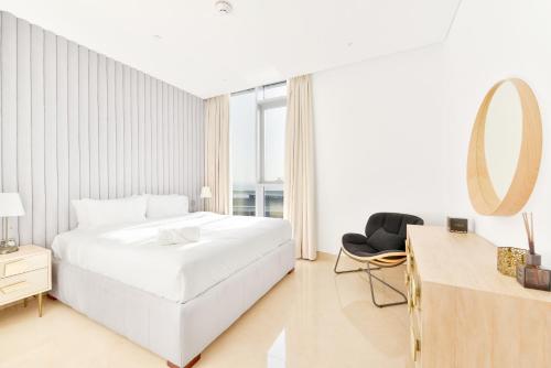 a white bedroom with a large bed and a mirror at Posh 2 BR Oceanfront Apt in the Heart of Bluewaters Island in Dubai