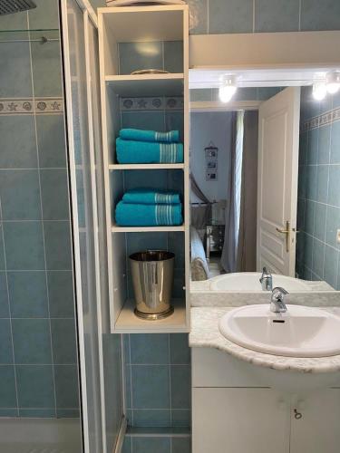une salle de bain avec un lavabo et une douche avec du carrelage bleu dans l'établissement Appartement sur la Plage, Le Royal Beach, à Saint-Laurent-du-Var