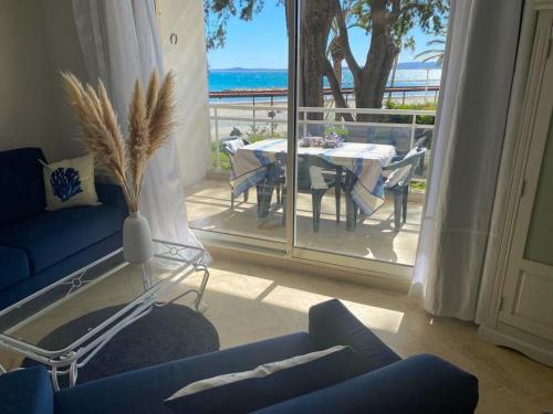 ein Wohnzimmer mit einem blauen Sofa und einem Tisch in der Unterkunft Appartement sur la Plage, Le Royal Beach in Saint-Laurent-du-Var