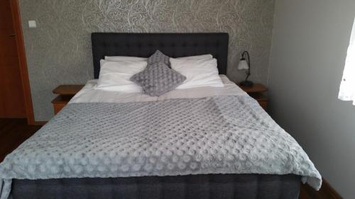 a bed with a gray comforter and two pillows at Villa Lena in Gdańsk