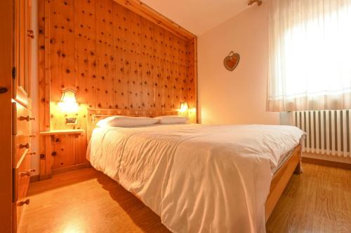 ein Schlafzimmer mit einem großen weißen Bett in einem Zimmer in der Unterkunft Majon Fior de Bosch 1 in Campitello di Fassa