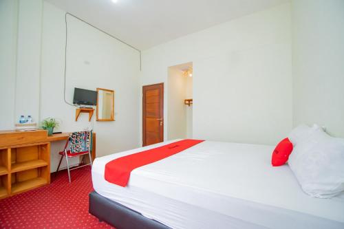 um quarto com uma grande cama branca e uma secretária em RedDoorz Syariah near Rembele Airport Bener Meriah em Tingkeum