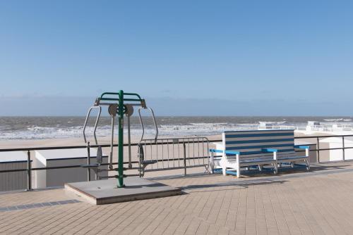 dos bancos y un poste de luz en una playa en Caravan Aan Zee Arnani en Middelkerke