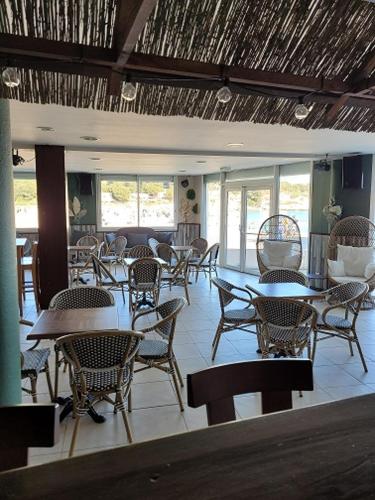 ein Esszimmer mit Tischen, Stühlen und Fenstern in der Unterkunft Le Pescadou in Martigues