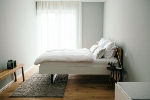 um quarto com uma cama com lençóis brancos e uma janela em Moselhaus by Clüsserath-Wittmann em Trittenheim