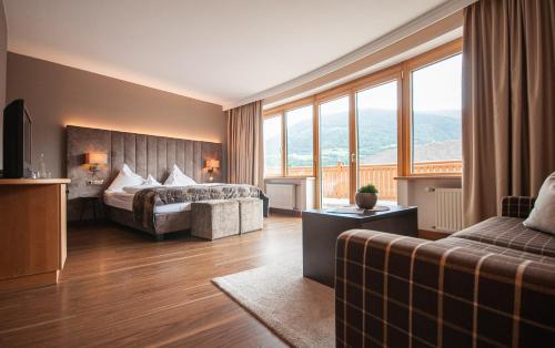 a hotel room with a bed and a couch at Klein Fein Hotel Anderlahn in Parcines