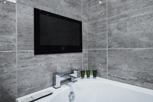 a bathroom with a television and a bath tub with a sink at Carlton Heights - A beautiful, inviting and modern 2 bedroom apartment, perfect for corporate stays and leisure in Nottingham