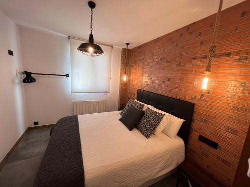 ein Schlafzimmer mit einem Bett mit Ziegelwand in der Unterkunft Alojamientos Rías Baixas - Mares del Forte- Cangas in Cangas