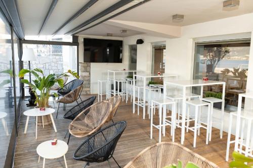 a restaurant with white tables and chairs and windows at Torbole Aparthotel in Nago-Torbole