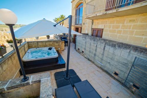 a hot tub on a balcony with an umbrella at Harbour Views Duplex Maisonette with Jacuzzi Hot tub in Mġarr