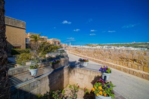 a retaining wall with potted flowers on it at Harbour Views Duplex Maisonette with Jacuzzi Hot tub in Mġarr