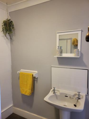 La salle de bains blanche est pourvue d'un lavabo et d'un miroir. dans l'établissement Troon Beach Town Golf Apartment Troon Ayrshire, à Troon