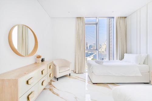 - une chambre blanche avec un lit et un miroir dans l'établissement Lavish & Equipped oceanfront 2 BR facing Ain Dubai, à Dubaï